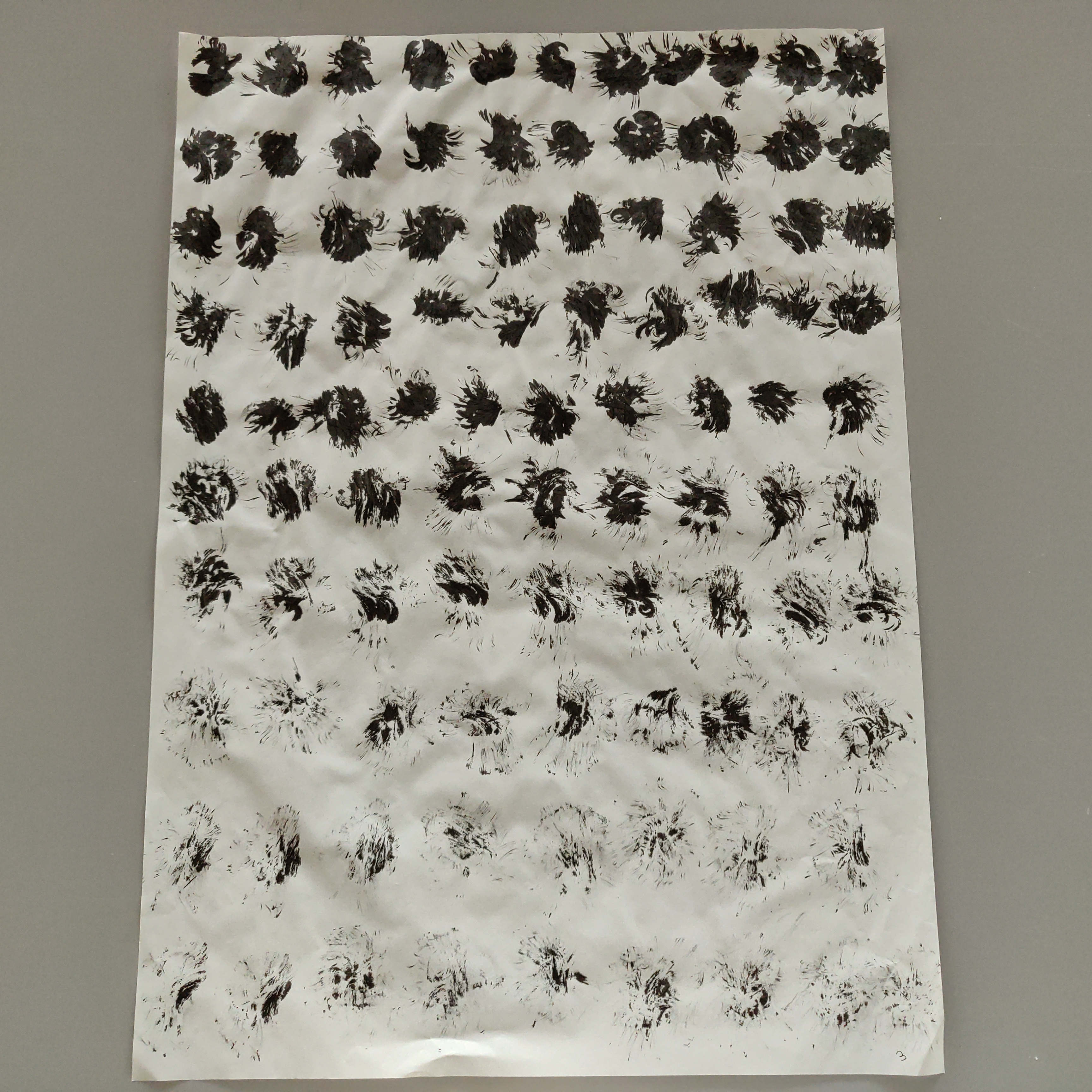 photograph of an abstract drawing, black ink on paper, rows of black dots that slowly dissipate and fade as the ink runs out