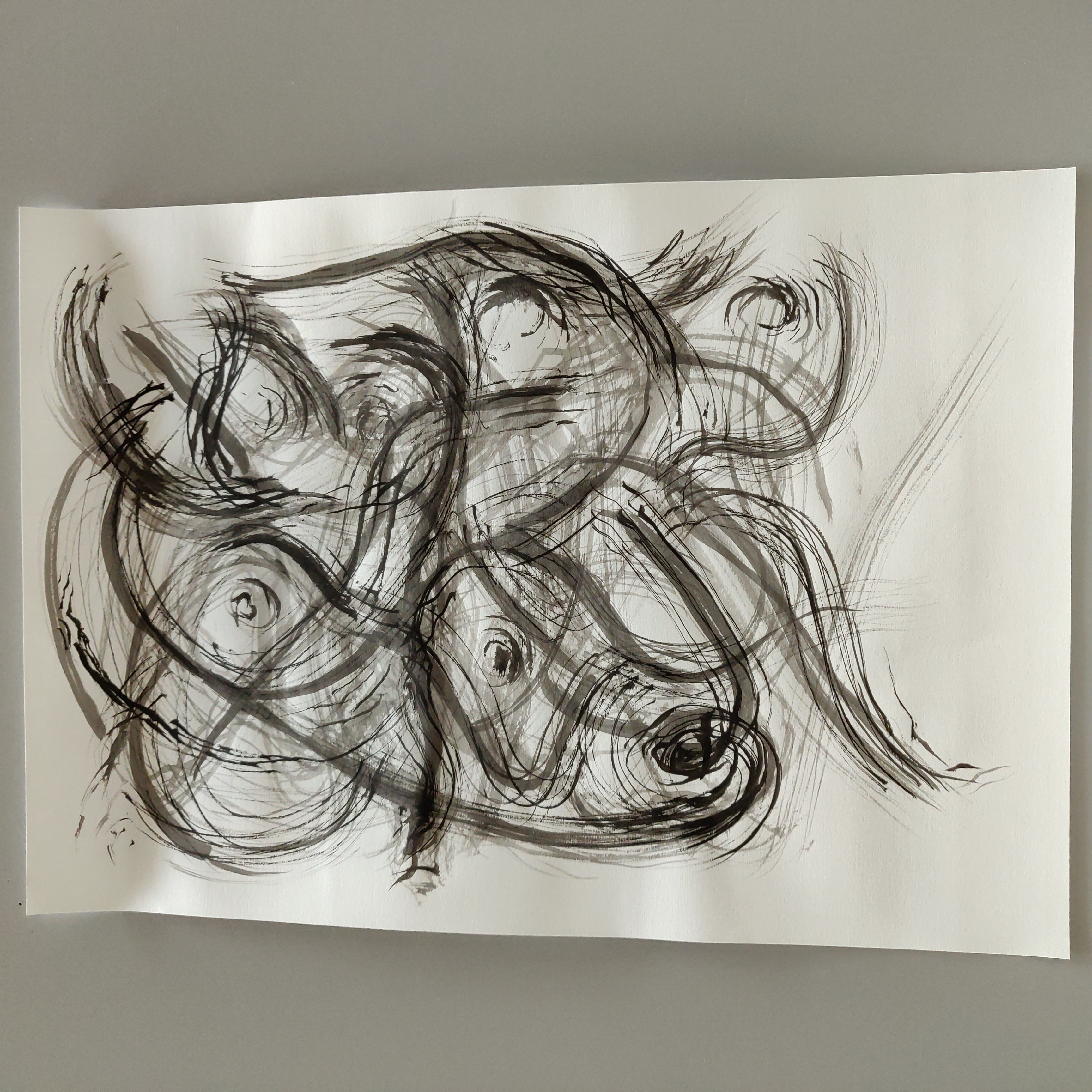 photograph of an abstract drawing, black ink on paper, swirling strokes of black ink criscrossing one another, punctuated by circluar dots of ink